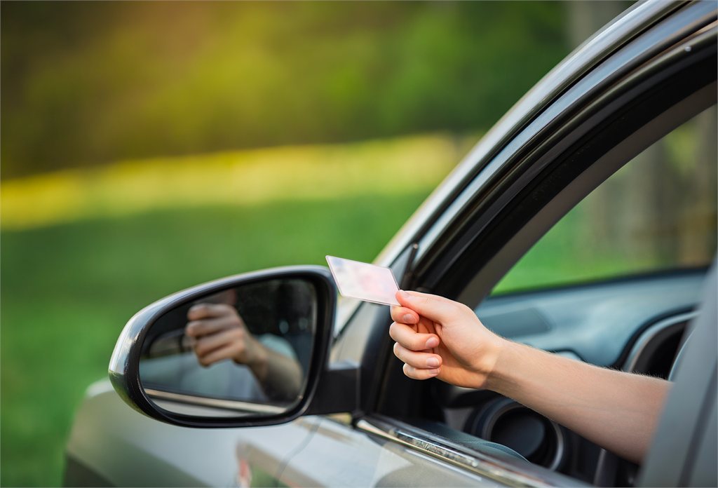 Mano che porge la patente dal finestrino di un'auto