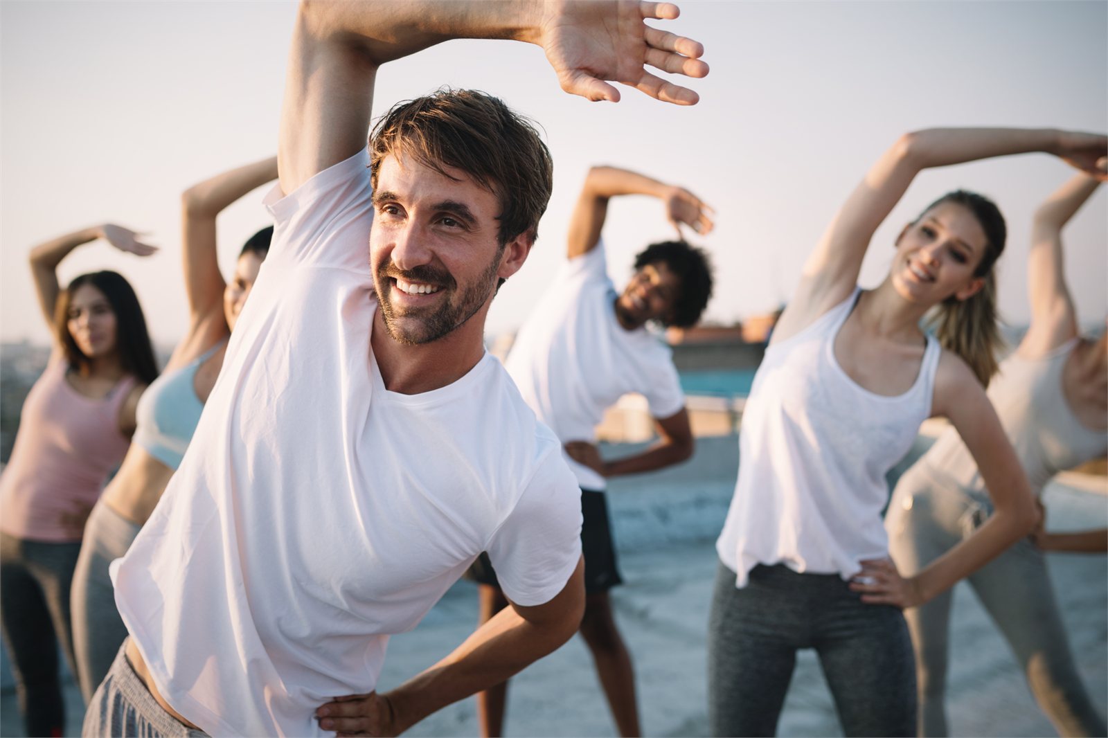 Gruppo di persone che fa stretching in riva al mare