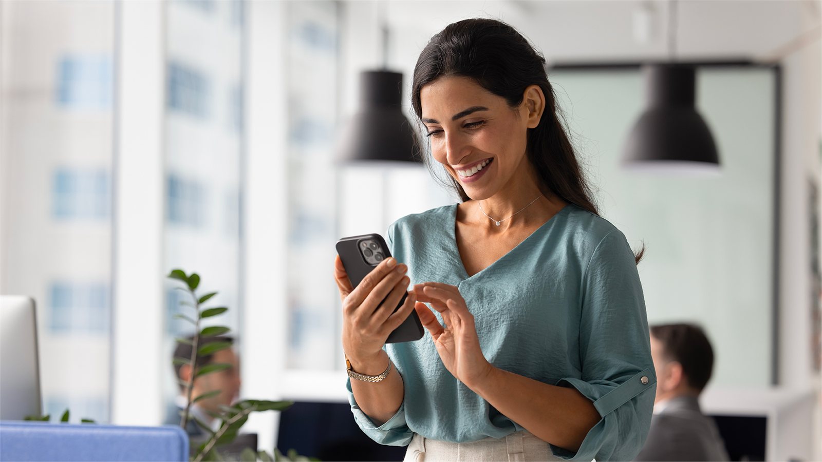 Donna sorridente che consulta lo smartphone in un ufficio luminoso